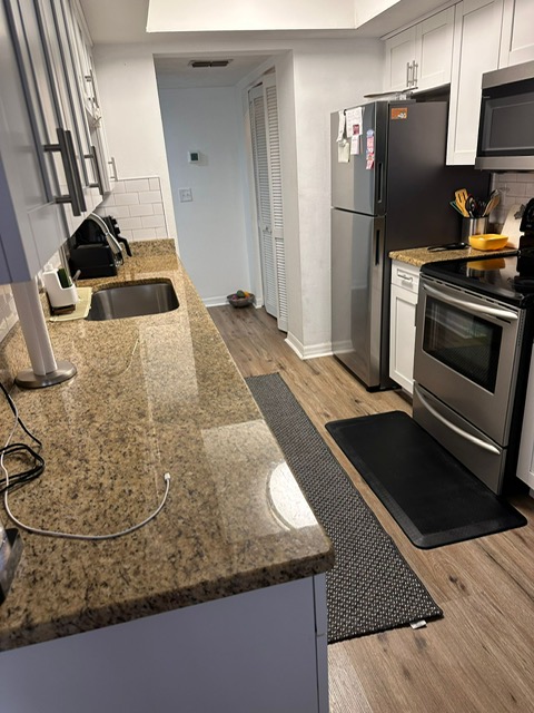 Professional cleaner from Vicilla's Cleaning Solutions wiping kitchen stovetop in Tampa Bay home